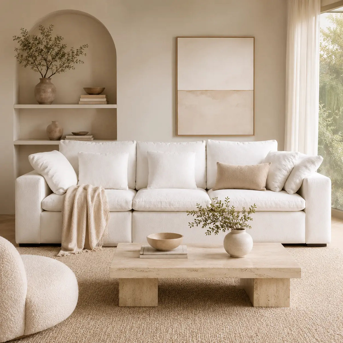 A modern white sectional sofa in a warm, minimalist living room with beige walls, a low wooden coffee table, and neutral decor.