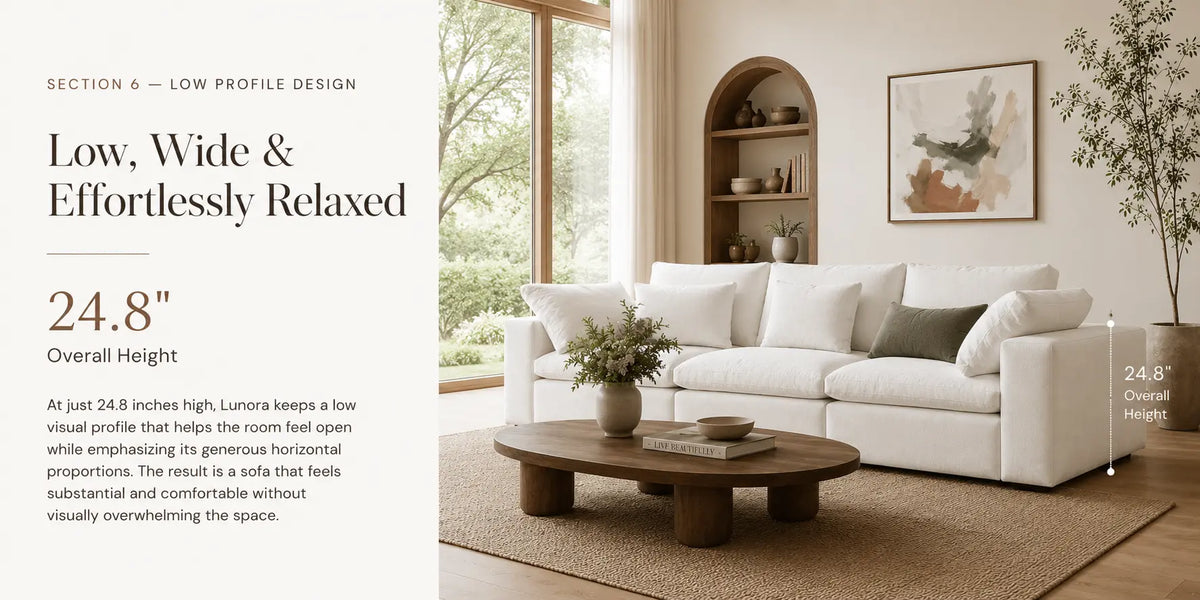A styled interior scene showing a low-profile white sofa in a bright living room, with text on the left describing the sofa's low, wide, and effortlessly relaxed profile. The room includes a wooden coffee table, beige rug, wall shelves, framed art, and a tall plant.