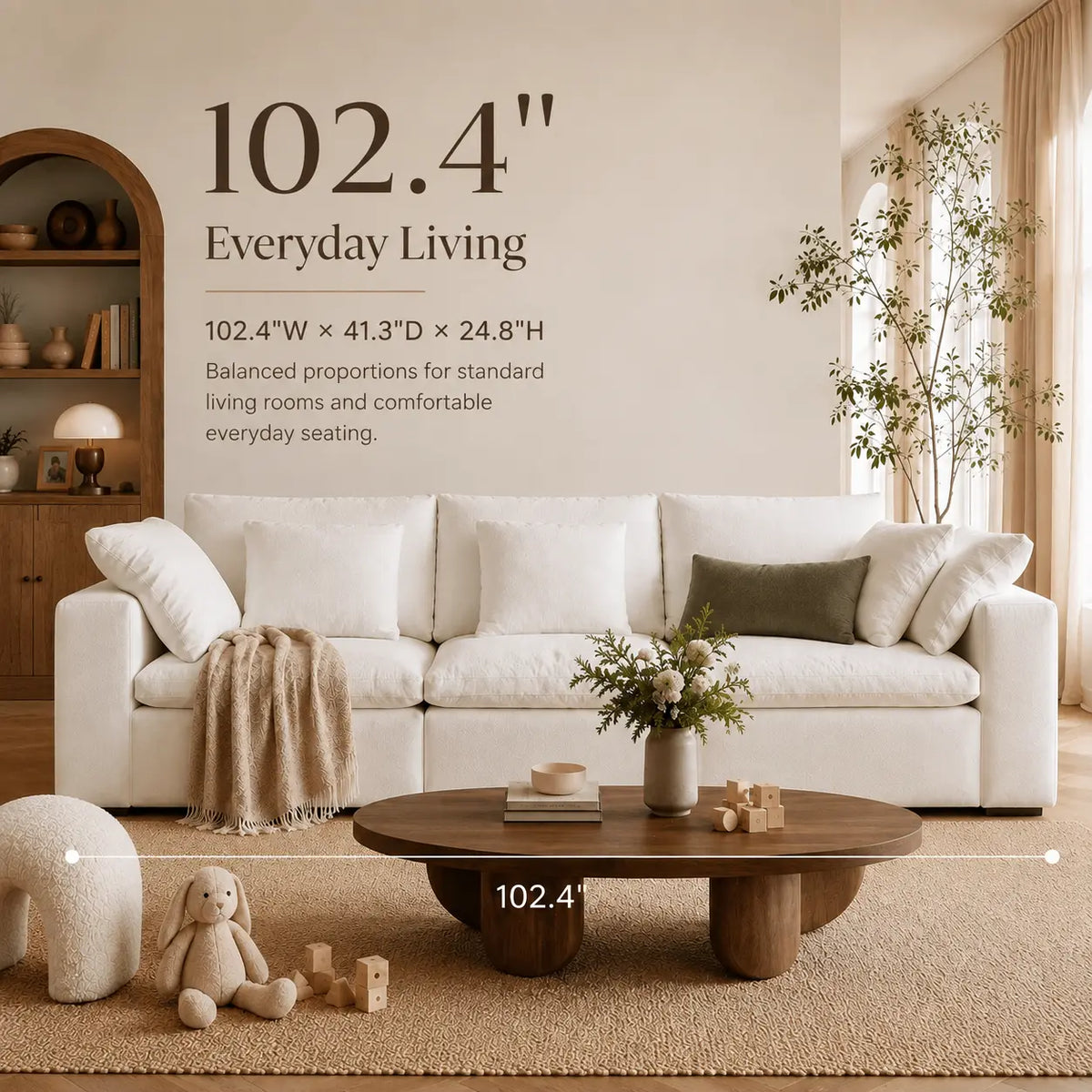 A styled living room scene showing a white sectional sofa in a warm beige interior, with wall text reading '102.4" Everyday Living' and a coffee table in front.